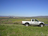 NWCC truck parked in a field overlooking a city in the distance. NWCC can evaluate potential building sites for clients